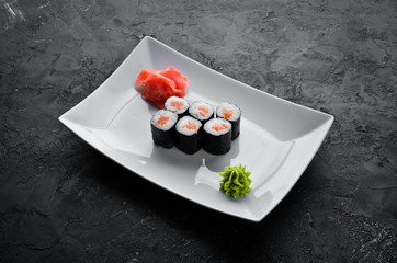 Sushi roll maki with salmon. Japanese cuisine. Top view. On a black stone background.
