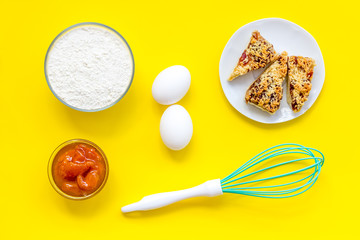 Cook cookies at home concept. Ingredients and instruments for make cookies. Fresh cookies near flour, eggs and whisk on yellow background top view