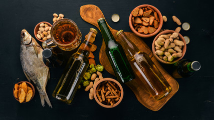 A selection of beer and snacks. Light beer, dark beer, live beer. On a black wooden background. Free space for text. Top view.