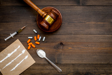 Drugs addiction, arrest for drugs. Pills, spoon with powder, syringe on dark wooden background top...