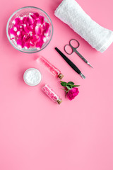 manicure equipment with spa salt and rose petals pink background top view space for text