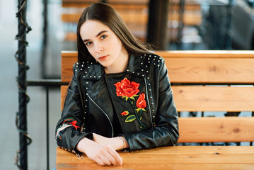 Portrait of a young punk rock fashion girl wearing black leather jacket with studs in urban warehouse street environment