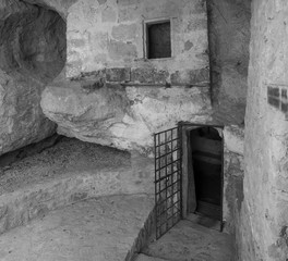 Entrance open dor to dungeon thomb or prison cell with rusted iron grate on medieval castle, black and white, copy space