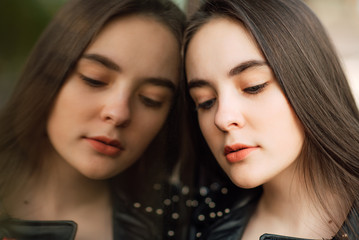 Portrait young punk rock fashion girl in black leather jacket with stilettos in an urban environment of a street warehouse,woman and reflection in the glass