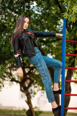 Portrait young punk rock fashion girl in black leather jacket with stiletto in a street warehouse urban environment, woman in jeans in the park
