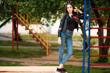 Portrait young punk rock fashion girl in black leather jacket with stiletto in a street warehouse urban environment, woman in jeans in the park