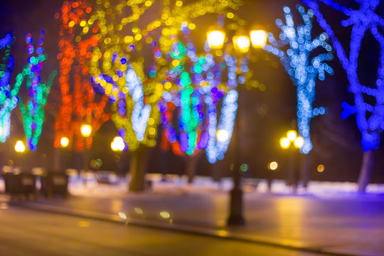Defocus the Christmas city at night. Rosly-colored garland on the trees