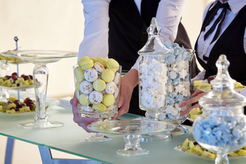 The hands of the waiters putting sweets on the table