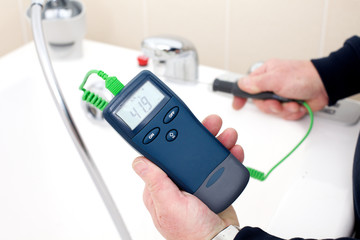 Using a digital thermometer with probe to measure the tempreture of hot tap water © mjgmedia