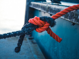 Two different colored ropes tied together at a mooring - 236854404