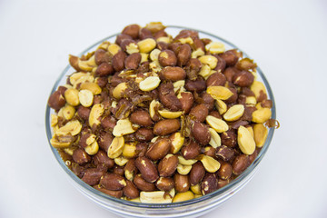 Roasted peanuts in glass bowl on white background