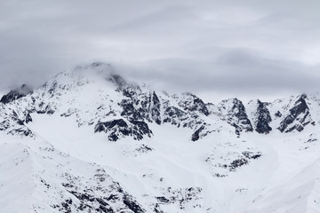 Fototapeta na wymiar Mountains in snow and cloudy gray sky before snowfall