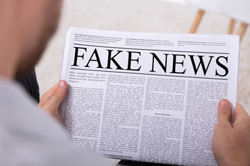 Man Holding Newspaper With Fake News