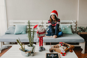 .Sweet and cheerful woman enjoying christmas at her home. Wearing christmas costume and eating...