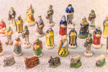 Small figurines of santons from French Provence used like beans of the cake of the kings during the Epiphany also called the Little Christmas on a glitter silver snow background.