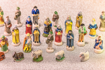 Small figurines of santons from French Provence used like beans of the cake of the kings during the Epiphany also called the Little Christmas on a glitter silver snow background.