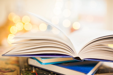 Open book is on top of the stack on bokeh background