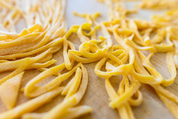 (selective focus) Fresh pasta called 'Fettuccine' made from fresh eggs and durum wheat flour. Fettuccine is a flat thick pasta popular in Roman and Tuscan cuisine.