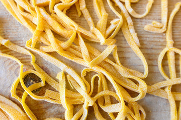 (selective focus) Fresh pasta called 'Fettuccine' made from fresh eggs and durum wheat flour. Fettuccine is a flat thick pasta popular in Roman and Tuscan cuisine.