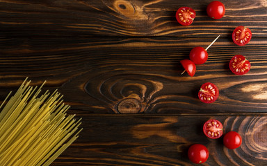 Spaghetti and cherry tomatoes on wooden background