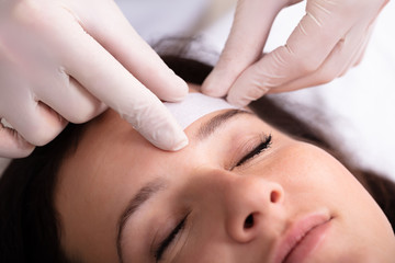 Obraz na płótnie Canvas Doctor Waxing Woman's Forehead