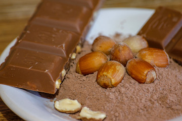 Cocoa, hazelnut and chocolate with hazelnut on wooden table. Close-up photo with vintage background.