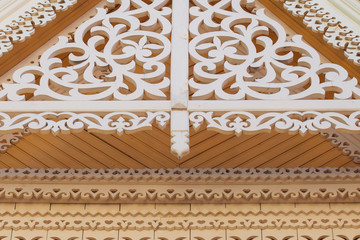 Carved wooden trim of the building. Yellow walls of the building and white carved patterns. The...