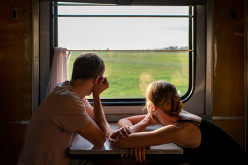 Couple of lovers traveling in train. Mood portrait of romantic pair in wagon looking at window with...