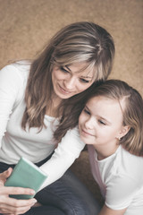 People, family and technology concept - happy girl and mother with smartphone at home