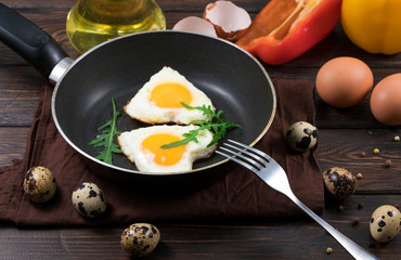 Fried eggs on a skillet on a wooden background