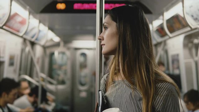 Serious beautiful European businesswoman tired and stressed on the subway train, looking around with empty sad eyes.
