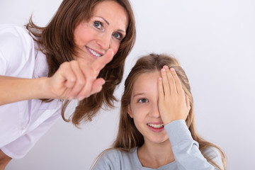 Optometrist Assisting Girl While Checking Eyesight