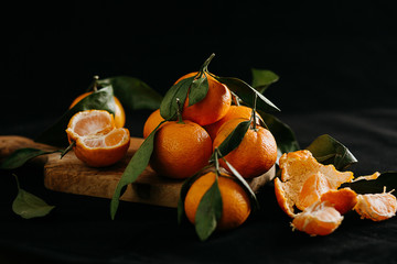 Ripe tangerines with leaves on a black background