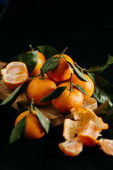 Ripe tangerines with leaves on a black background