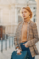Outdoor fashion portrait of young beautiful fashionable girl wearing trendy checkered blazer, beige...