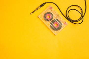 Retro cassette tape and audio jack on the yellow background. copy space