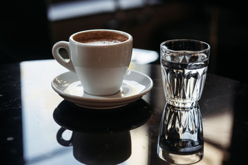 Close-up of a cup of coffee and glass of water on a table
