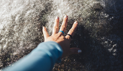 Woman's hand feels ice/rocks