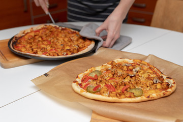 Baking a delicious pizza in a home kitchen. Slicing and stacking the baked pizza on the kitchen table.