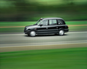 Fototapeta na wymiar London black taxi cab speeding along road