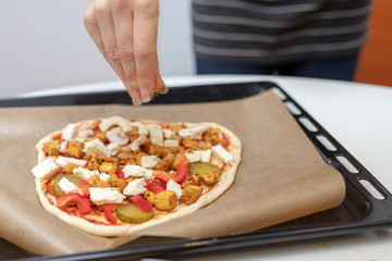 Preparation of a delicious pizza in a home kitchen. Laying and decorating pizza dough on the kitchen table.