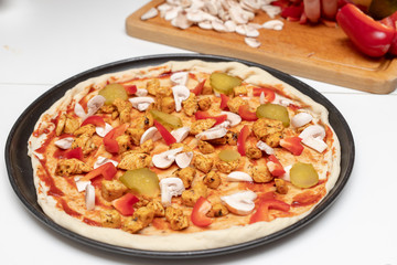 Preparation of a delicious pizza in a home kitchen. Laying and decorating pizza dough on the kitchen table.