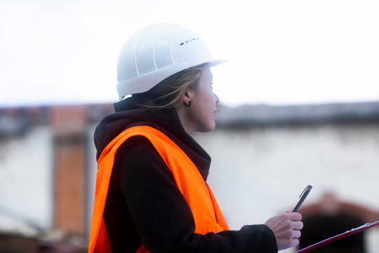 Portrait of a woman on a construction site writing on her clipboard
