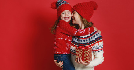 happy family mother and child daughter with christmas gifts on red background