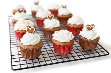 Spice cupcakes decorated with gingerbread hearts and candy cane crush, on white background
