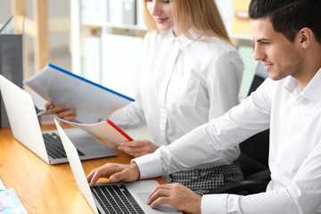 Obraz premium Young employees working with laptops and documents in office