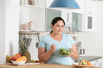 Woman with bowl of vegetable salad in kitchen. Healthy diet