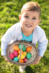 Cute little boy with basket of Easter eggs in park