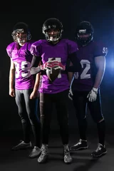 Fotobehang American football players in uniform on dark background © New Africa