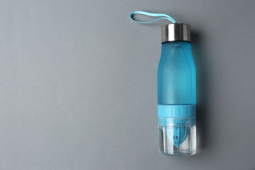Sport bottle with space for text on color background, top view